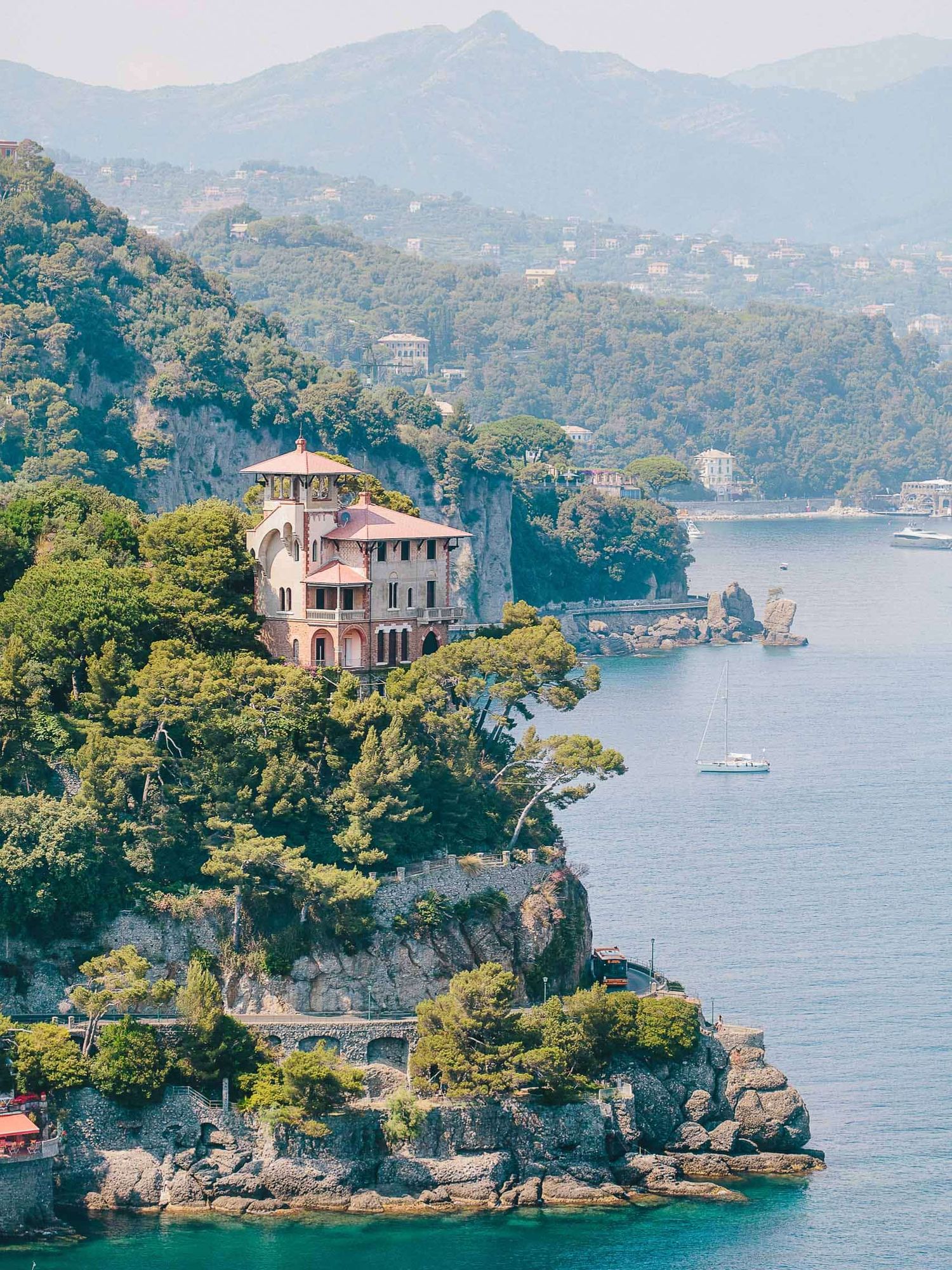 Historic villas perched on rocky cliffs along the Italian Riviera coastline.