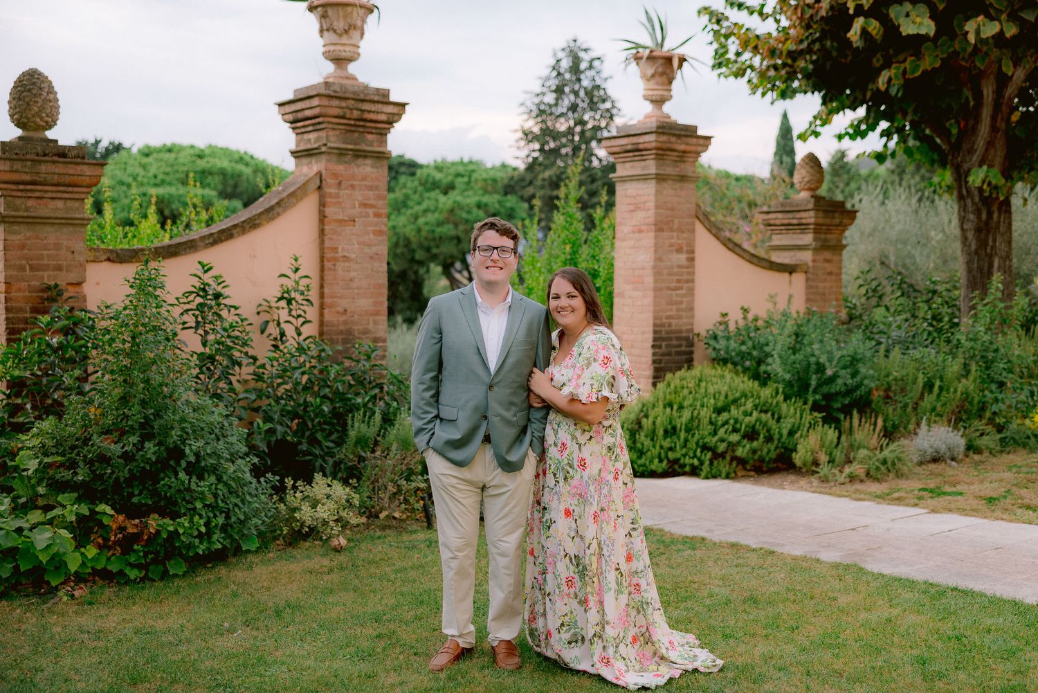 An elegant garden entrance with ornate stone pillars and lush greenery in Tuscany.