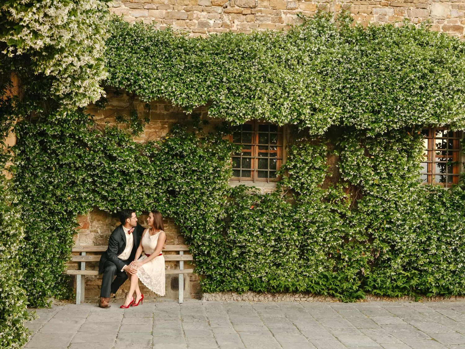 Romantic portraits against a lush ivy-covered wall in an Italian garden setting.