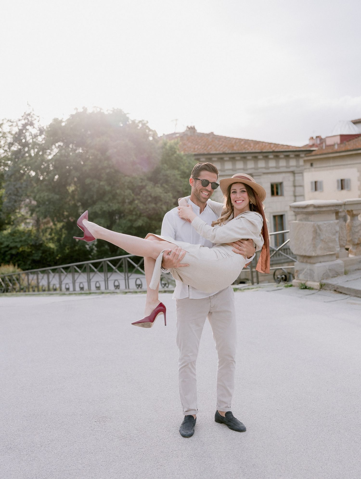 Playful moment captured outside an Italian villa with red heels and sunglasses.