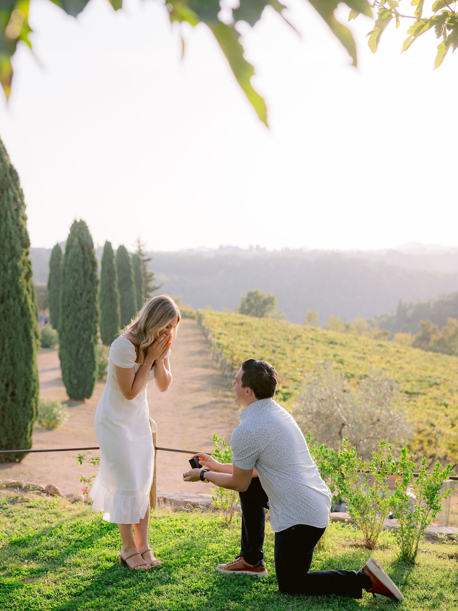 Couple sharing a romantic moment among cypress trees at sunset in Tuscany.