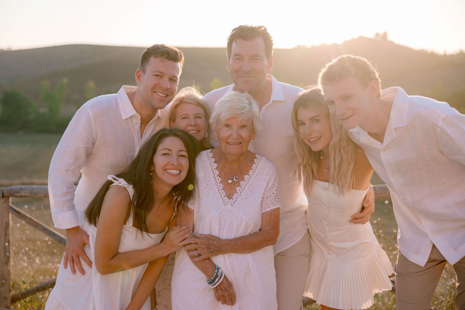 Family members embrace while taking photos during golden hour outdoors.