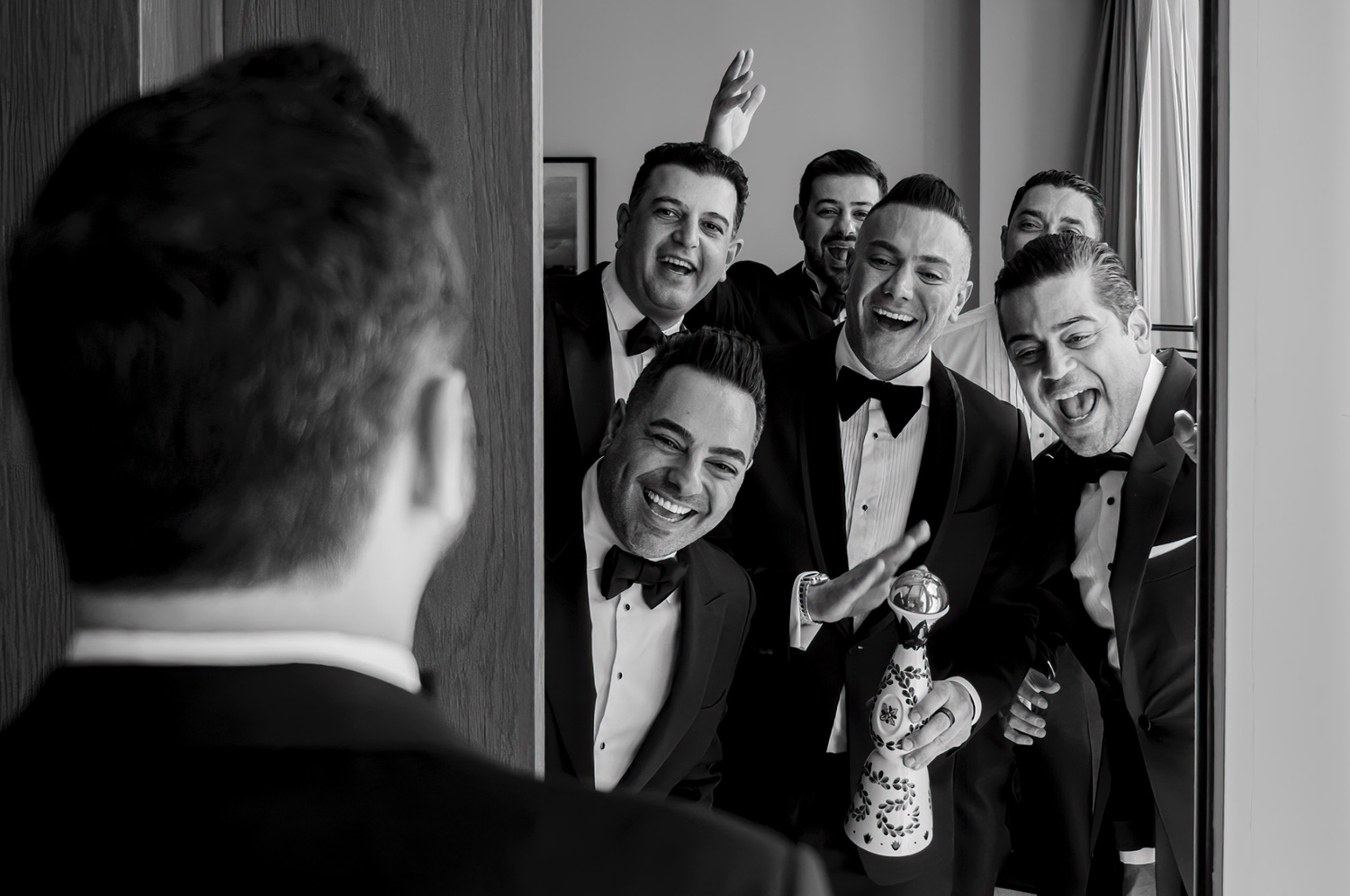 A series of black and white wedding photos showing joyful moments and laughter among groomsmen getting ready.