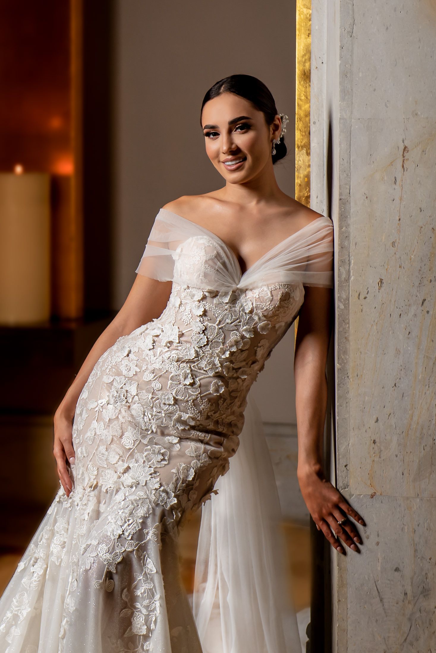 Close-up details of intricate floral lace appliques on an off-shoulder wedding gown.