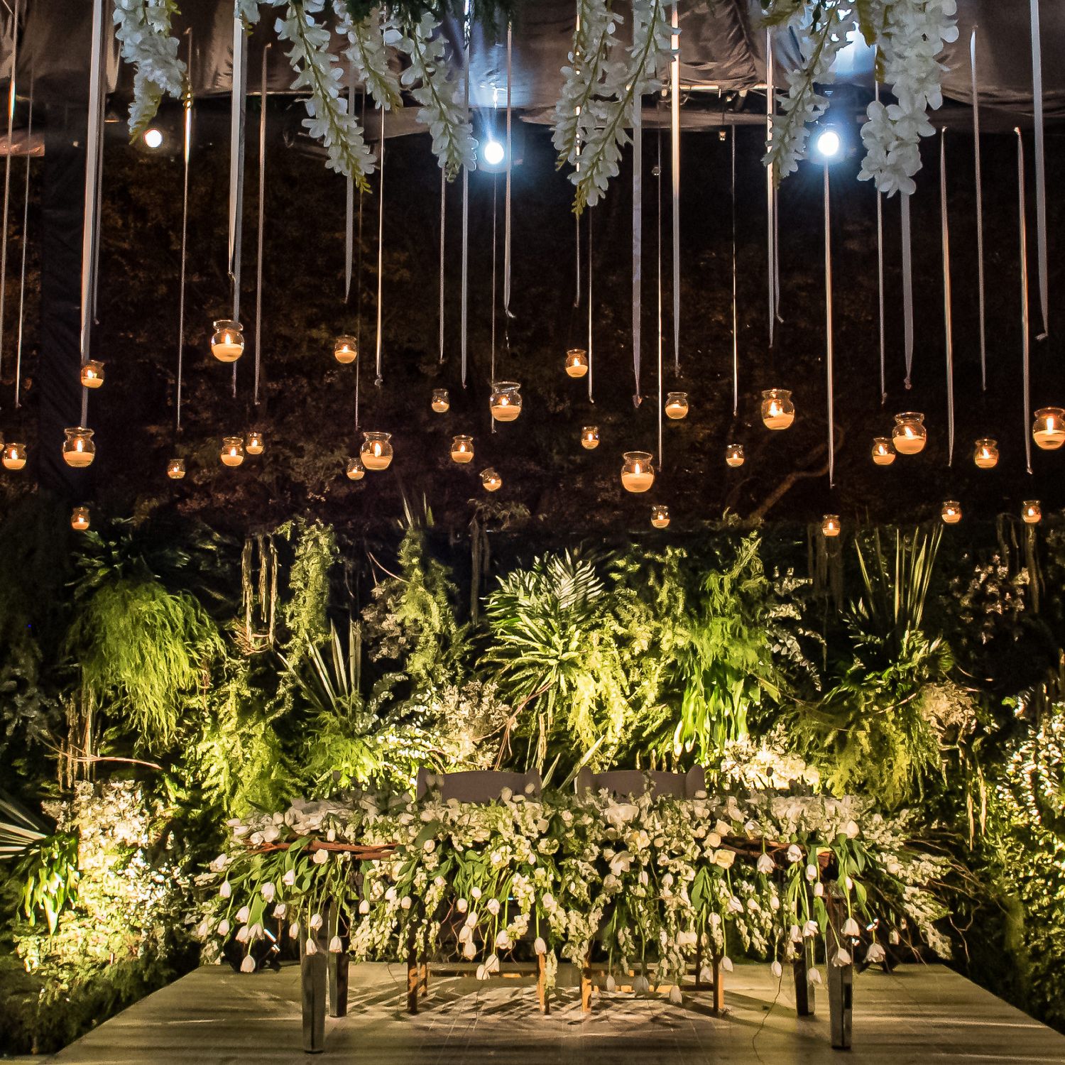 Elegant event space with hanging glass orbs and lush greenery creating a magical garden atmosphere.