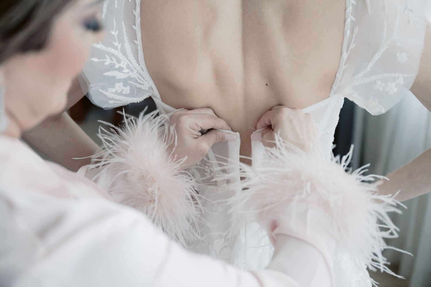 White feather boa and delicate lace details on wedding attire.