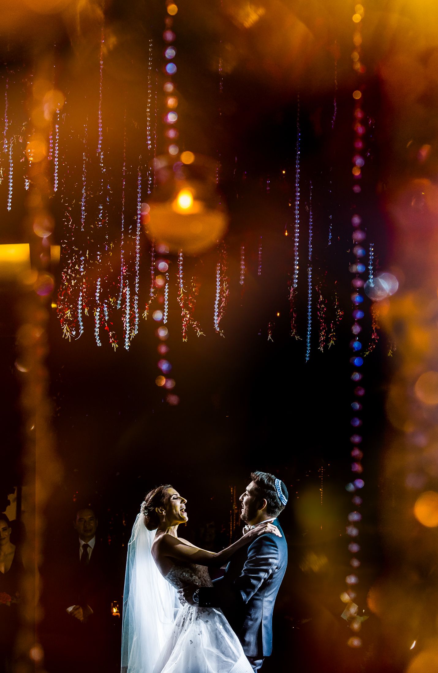 Couple dancing under suspended crystal decorations with warm golden lighting creating a dreamy atmosphere.