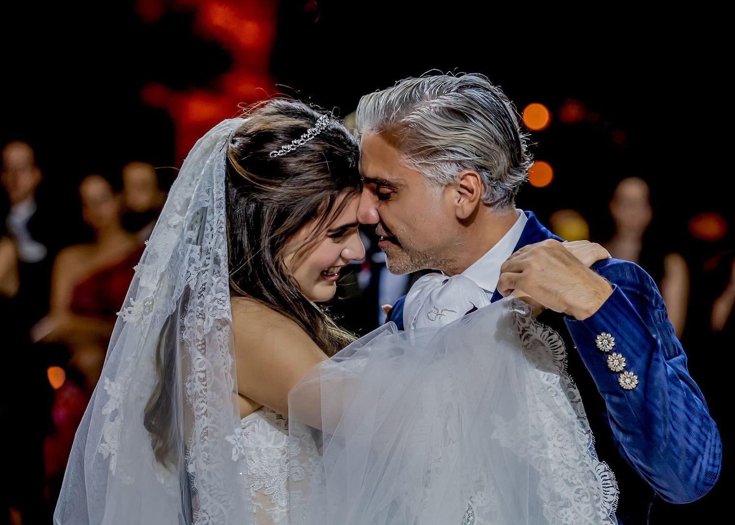 A romantic first dance moment at a wedding reception with dramatic lighting and bokeh effects.