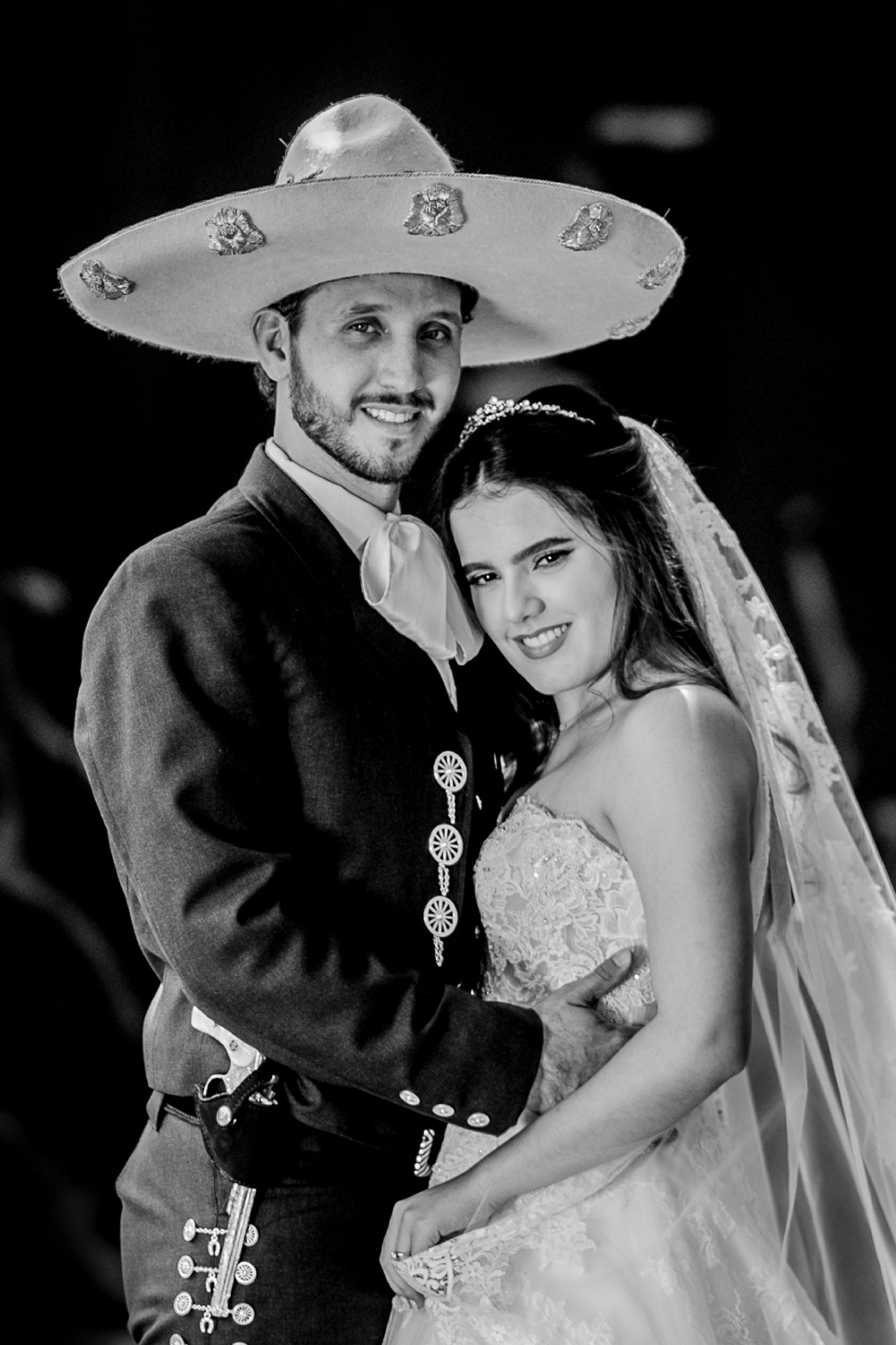 Wedding couple poses in traditional Mexican attire with the groom wearing an ornate sombrero.
