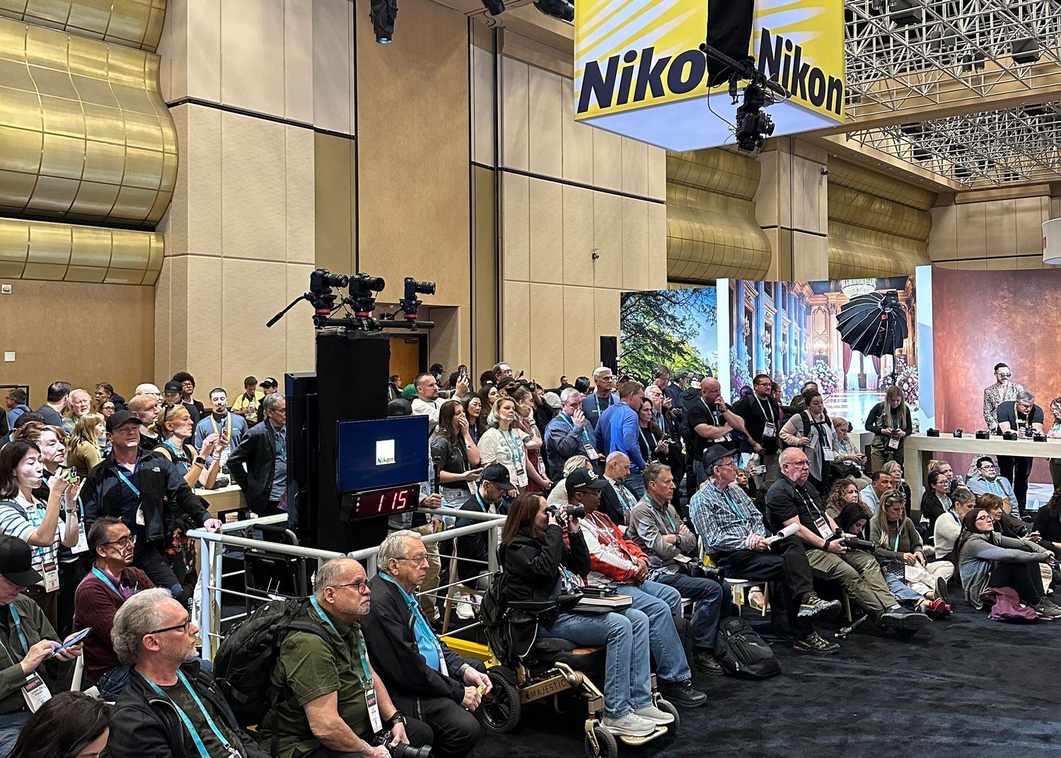 Conference audience seated in rows watching a photography presentation in a dimly lit venue.