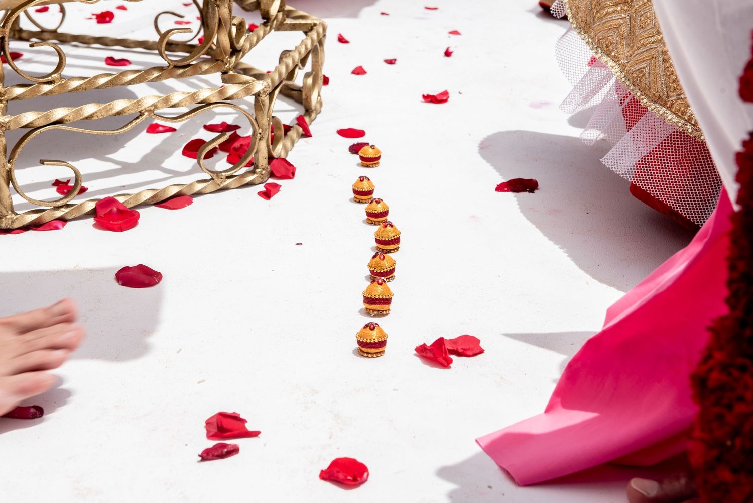 Red rose petals and decorative marigold garland on white floor at an Indian wedding ceremony.