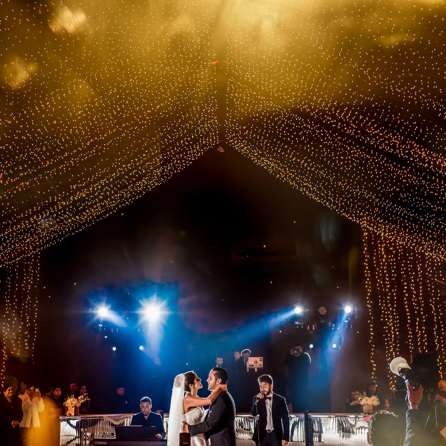 Wedding dance floor illuminated with string lights and blue spotlights creating a magical atmosphere.