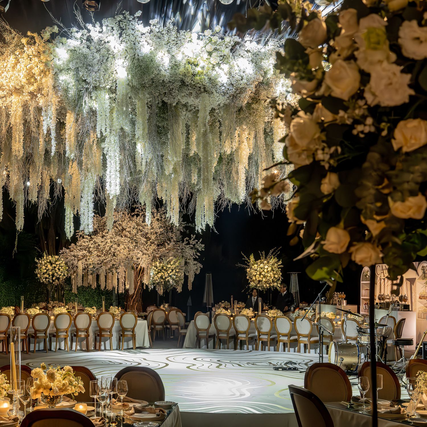Elegant wedding reception venue with cascading white fabric drapes and floral arrangements creating a romantic atmosphere.