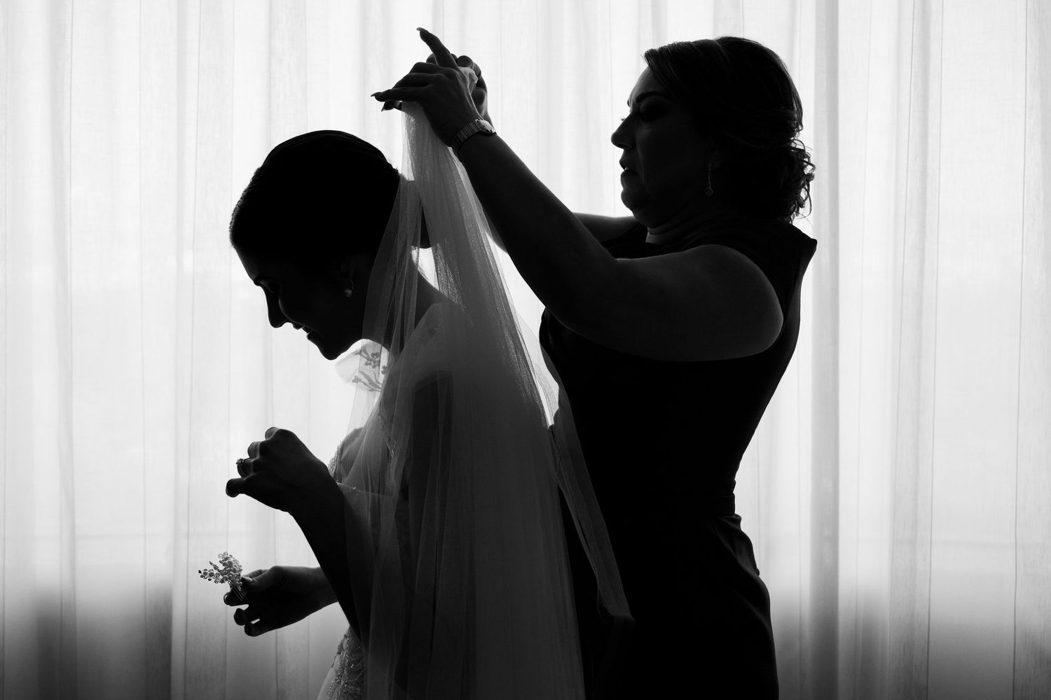 Silhouettes of people getting ready against white curtain backdrop.