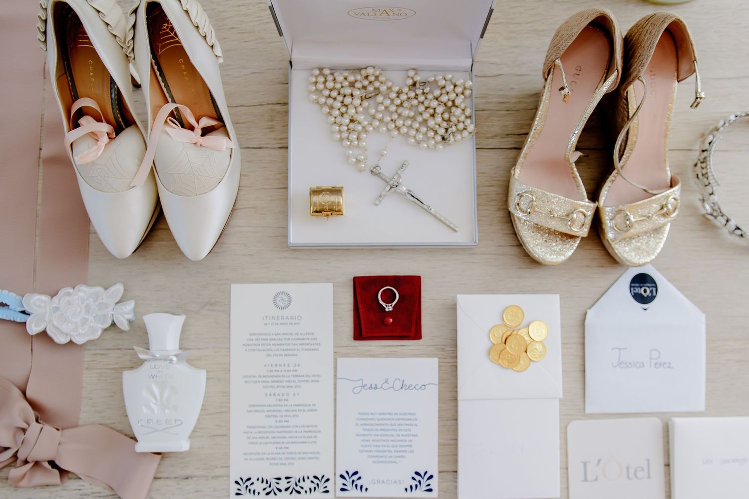 Wedding details flatlay with invitations, rings, shoes and delicate accessories.
