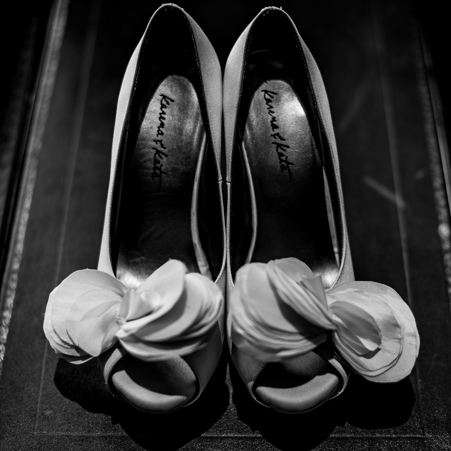 Elegant white bridal heels arranged symmetrically in dramatic black and white.