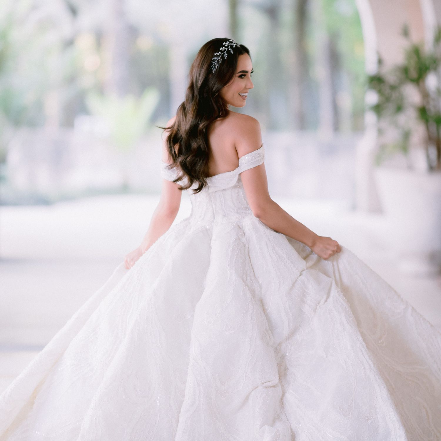 Romantic bridal portrait showing the back detail of an off-shoulder ball gown wedding dress.