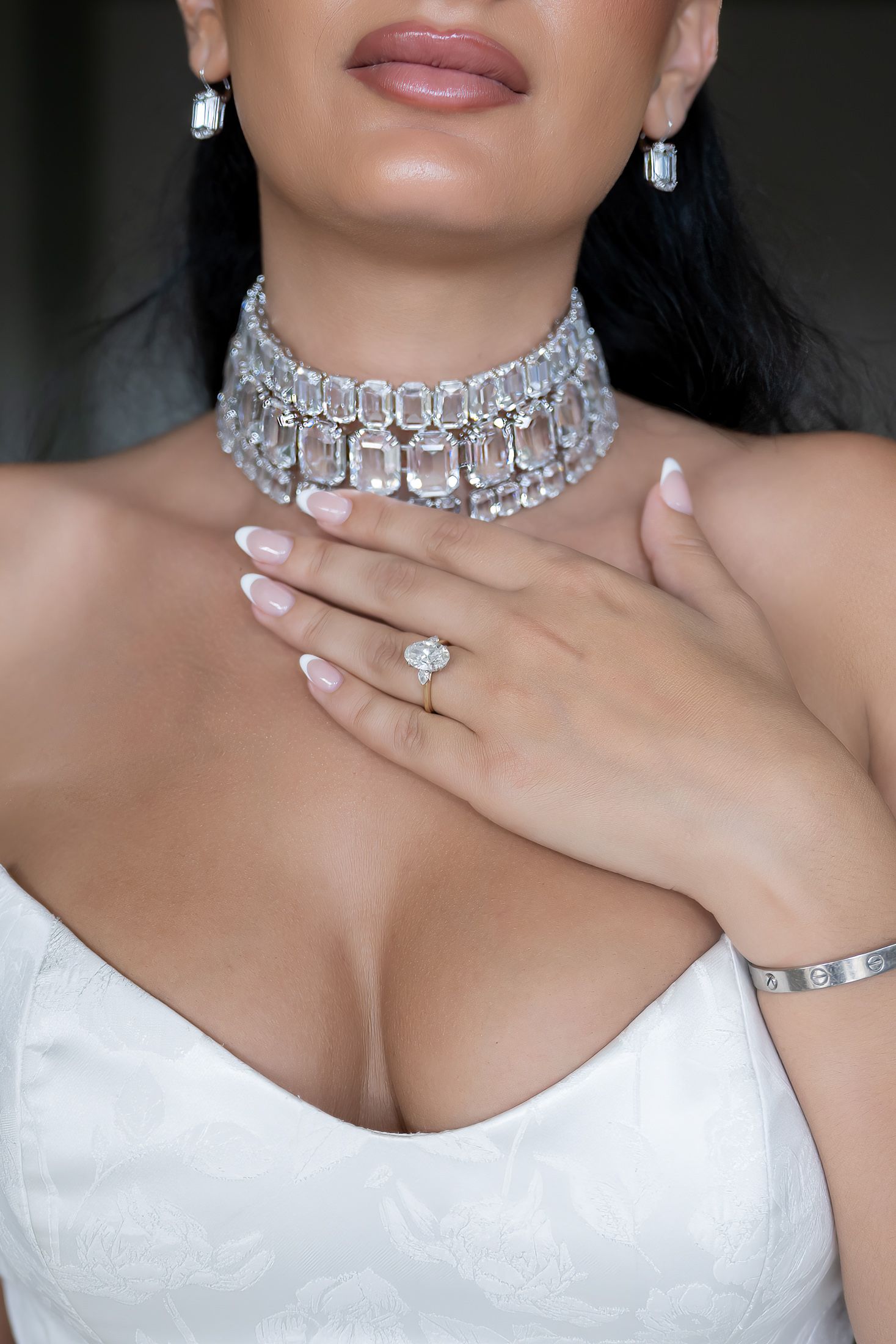 Elegant diamond choker necklace and jewelry on bride wearing white strapless gown.