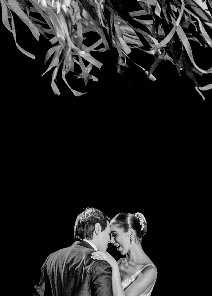Black and white romantic wedding portrait under hanging decorations.