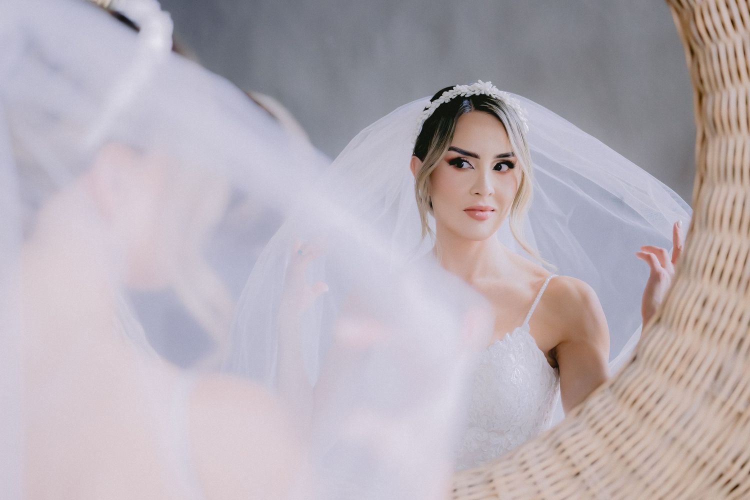 Ethereal bridal portrait with soft lighting and wicker chair details.