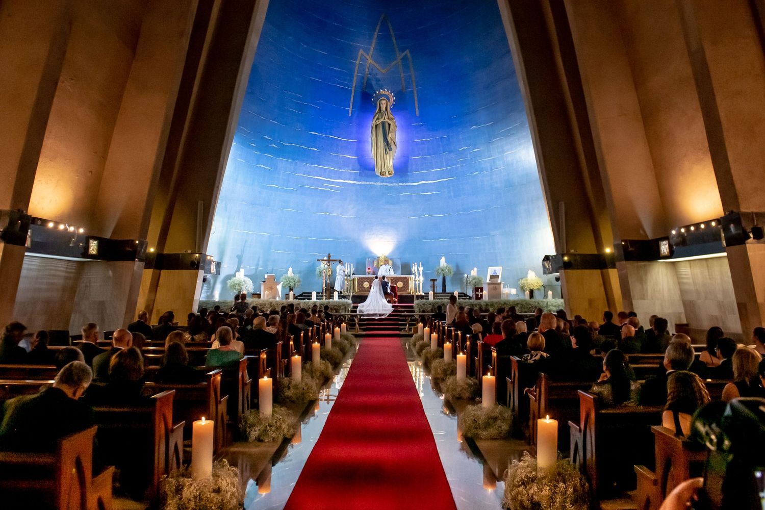 Modern church wedding ceremony with dramatic lighting and red carpet aisle.