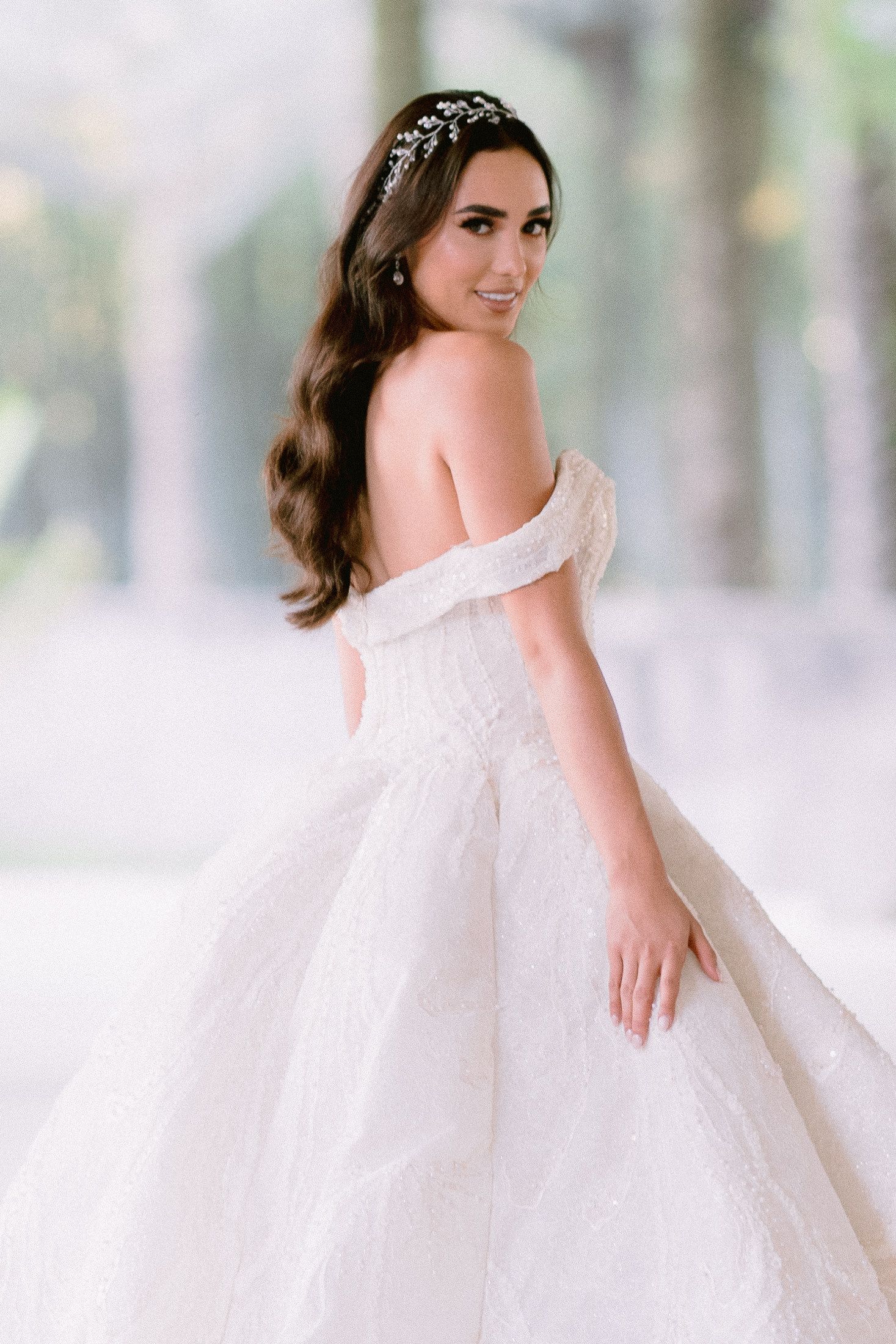 Stunning off-shoulder wedding gown with delicate beaded headpiece in an elegant setting.
