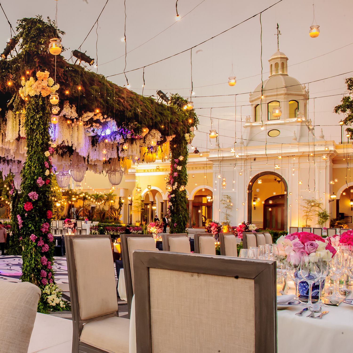 Formal dining setup with string lights and elegant table settings against a historic building backdrop.