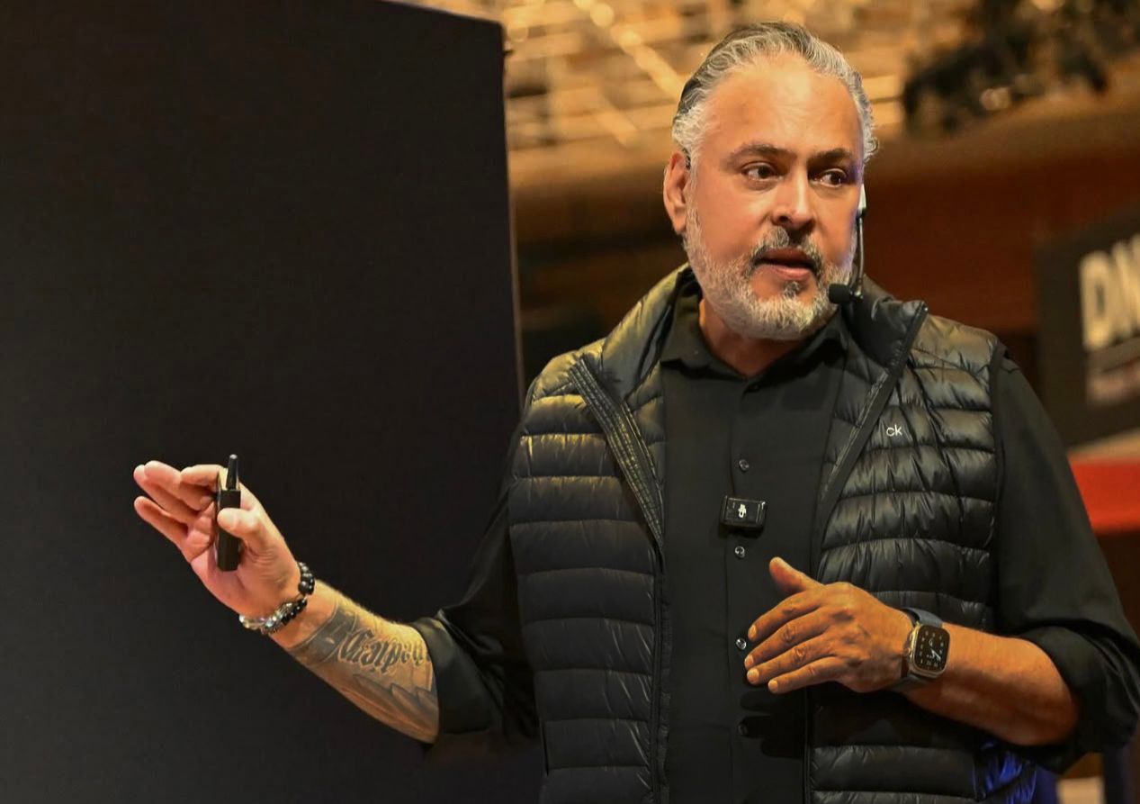 Speaker presenting on stage at a photography conference with dramatic lighting and black backdrop.