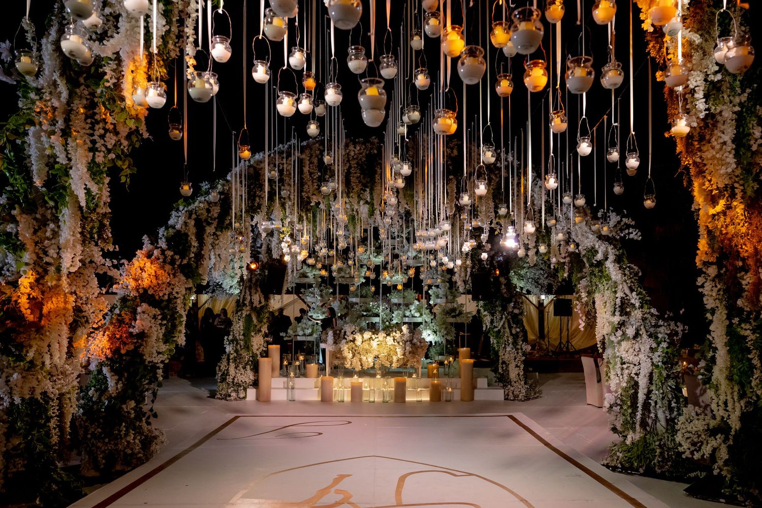 Enchanting overhead display of hanging lights and floral arrangements in warm amber tones.