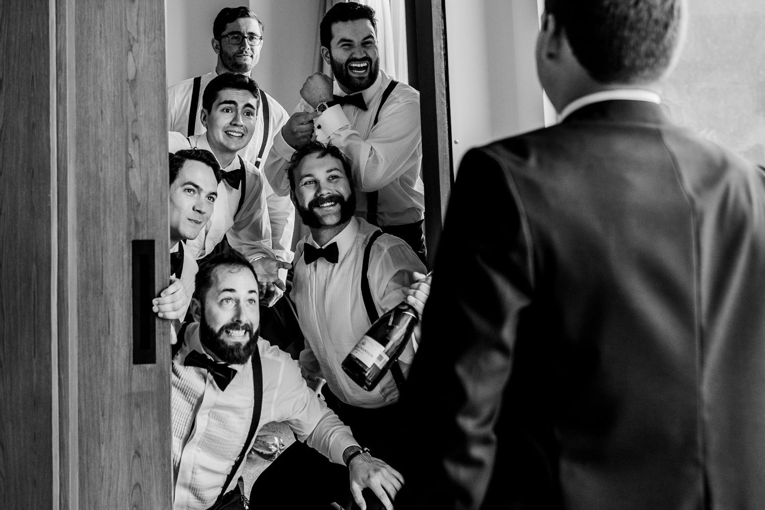 Candid black and white photos of groomsmen sharing laughs before the wedding.