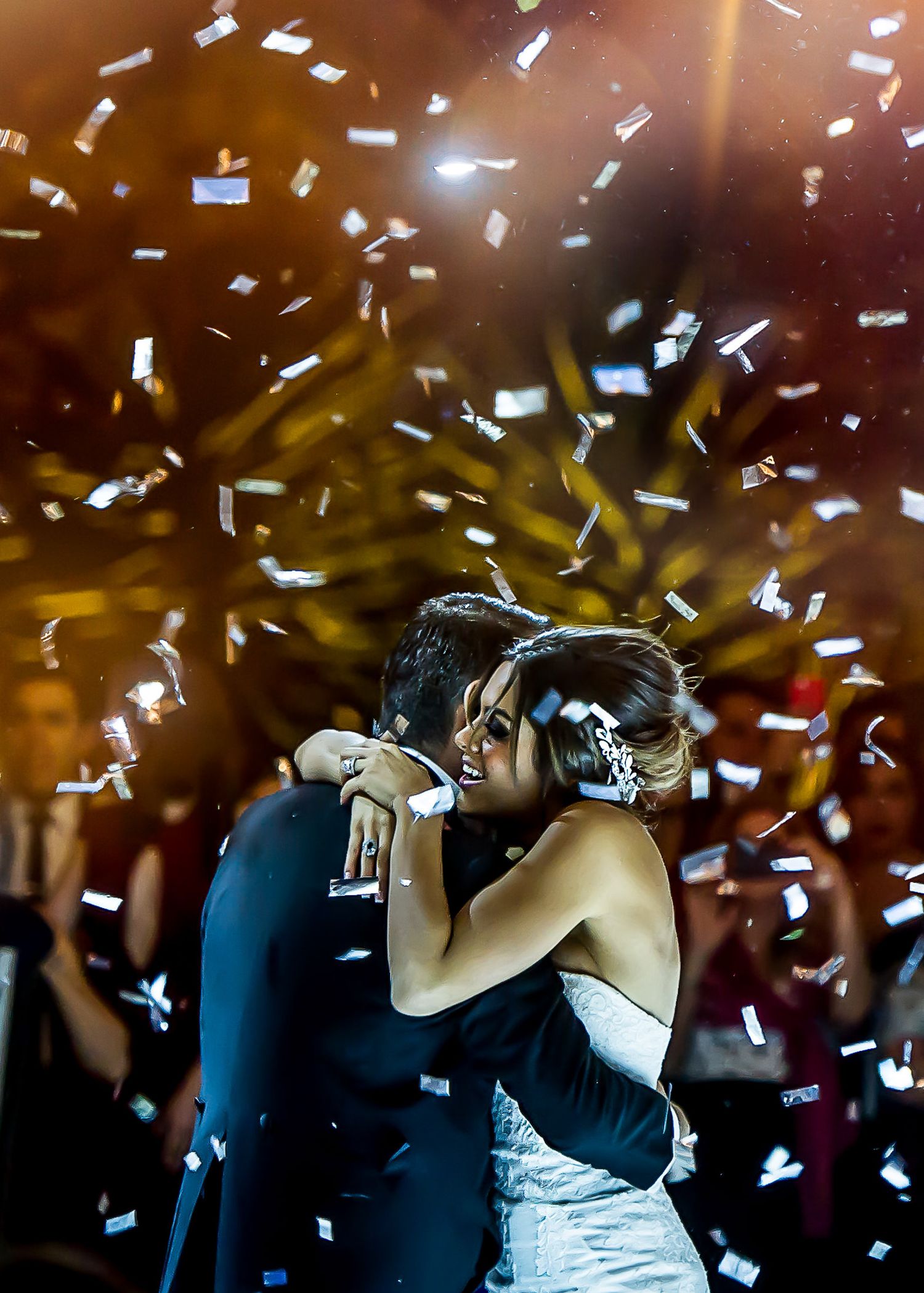 White confetti rains down during a romantic first dance at an elegant wedding reception.