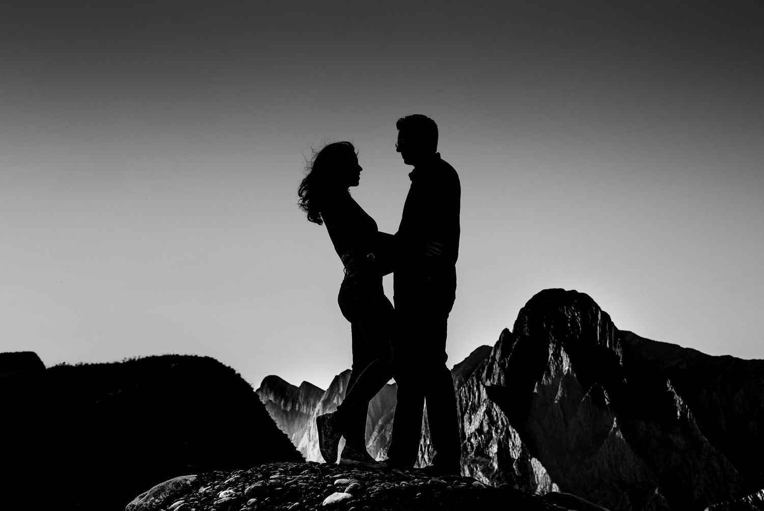 Silhouettes of people against dramatic mountain landscape at sunset.