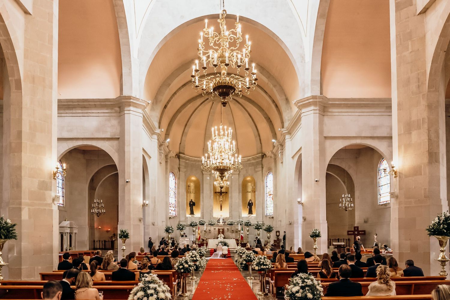 Elegant church wedding ceremony with grand chandeliers and classic architectural details.