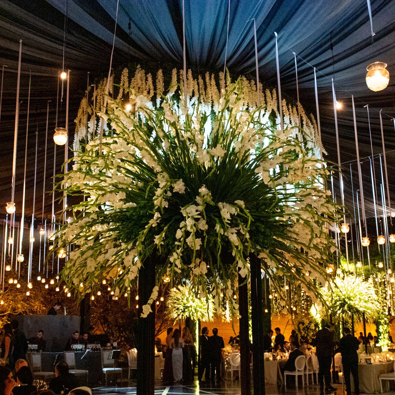 Dramatic ceiling installation featuring white floral arrangements and suspended lighting elements.