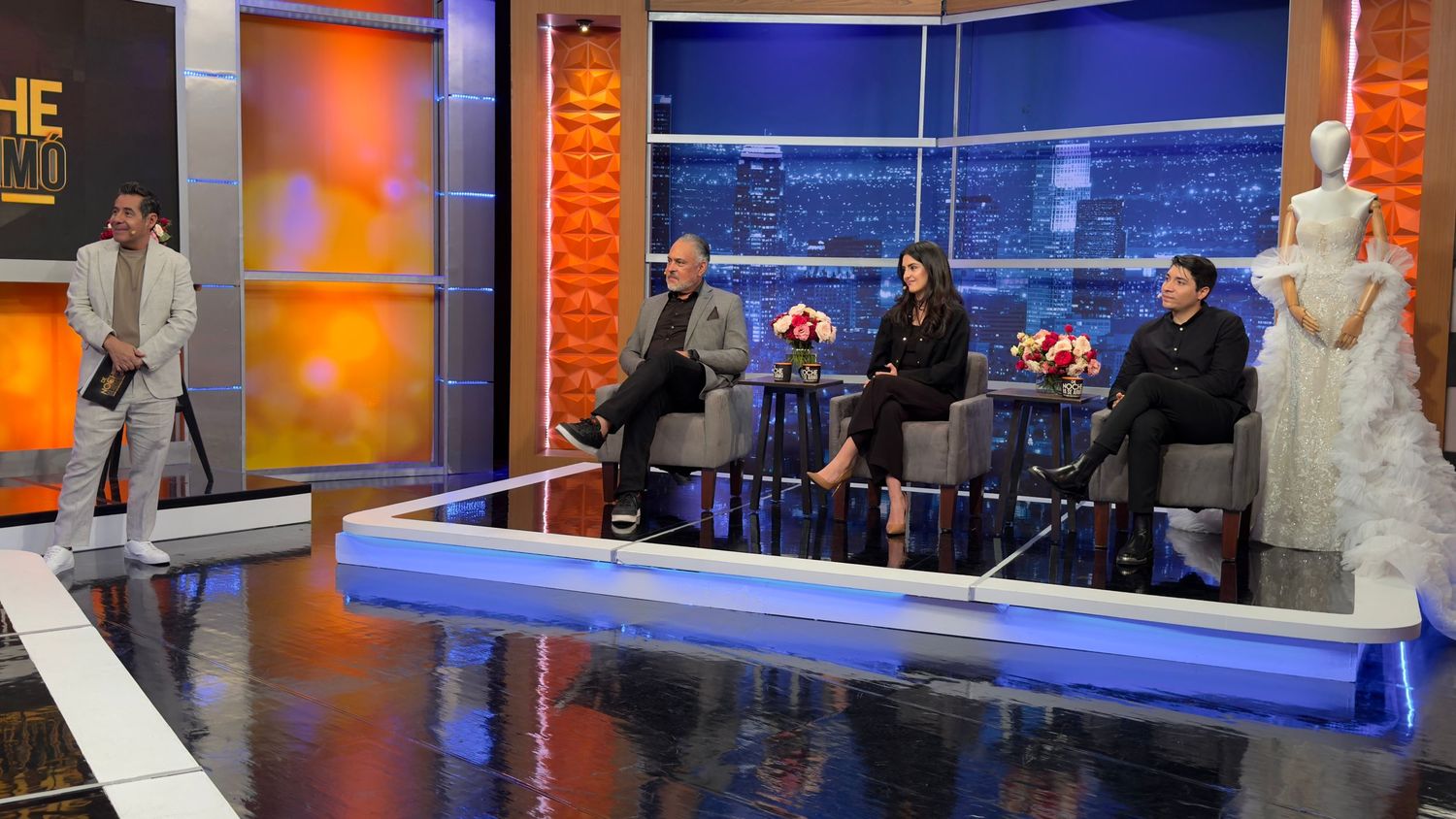 Television studio set with orange and blue lighting featuring sleek modern design elements.