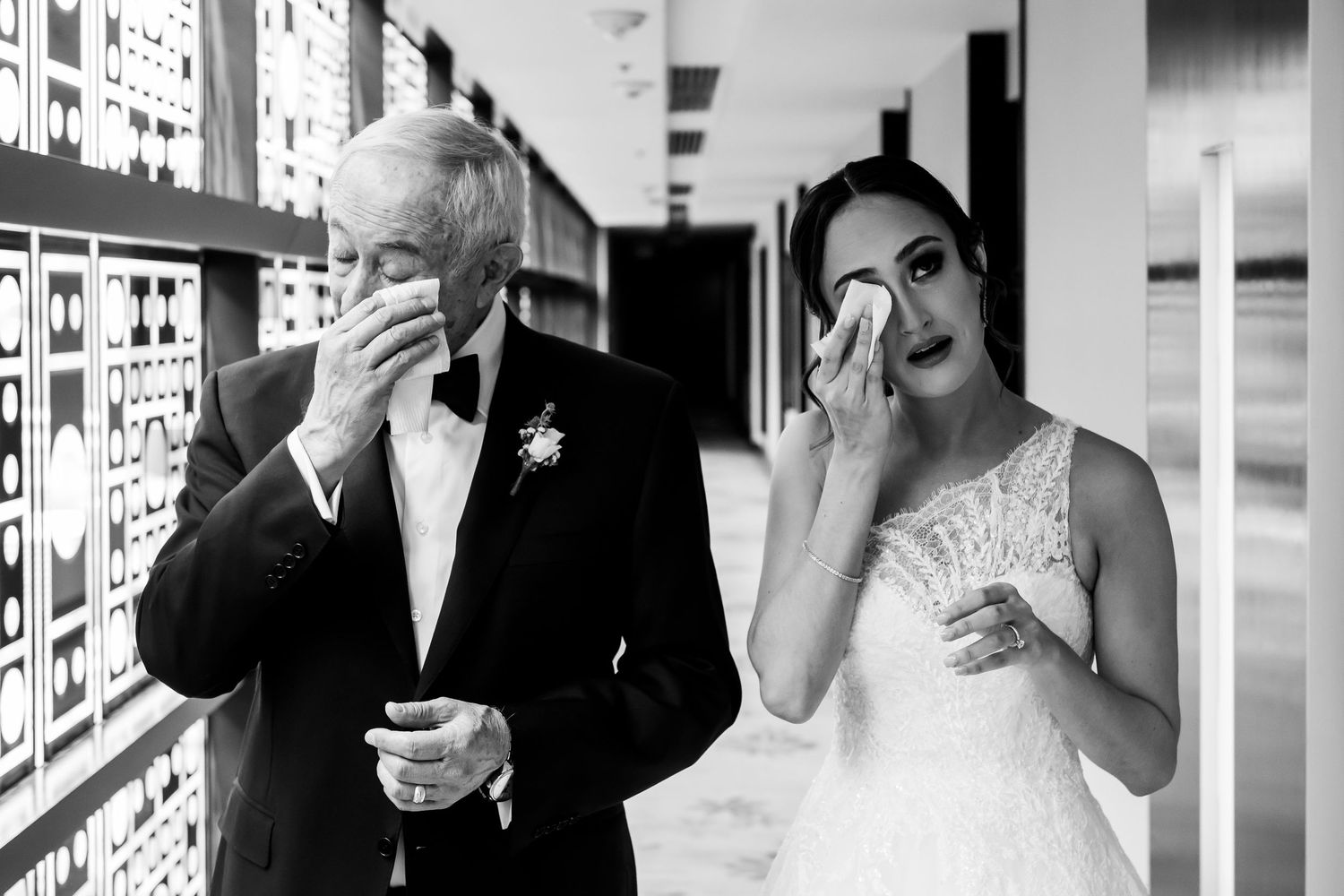 Black and white wedding party photo showing people laughing and drinking together in a candid moment.