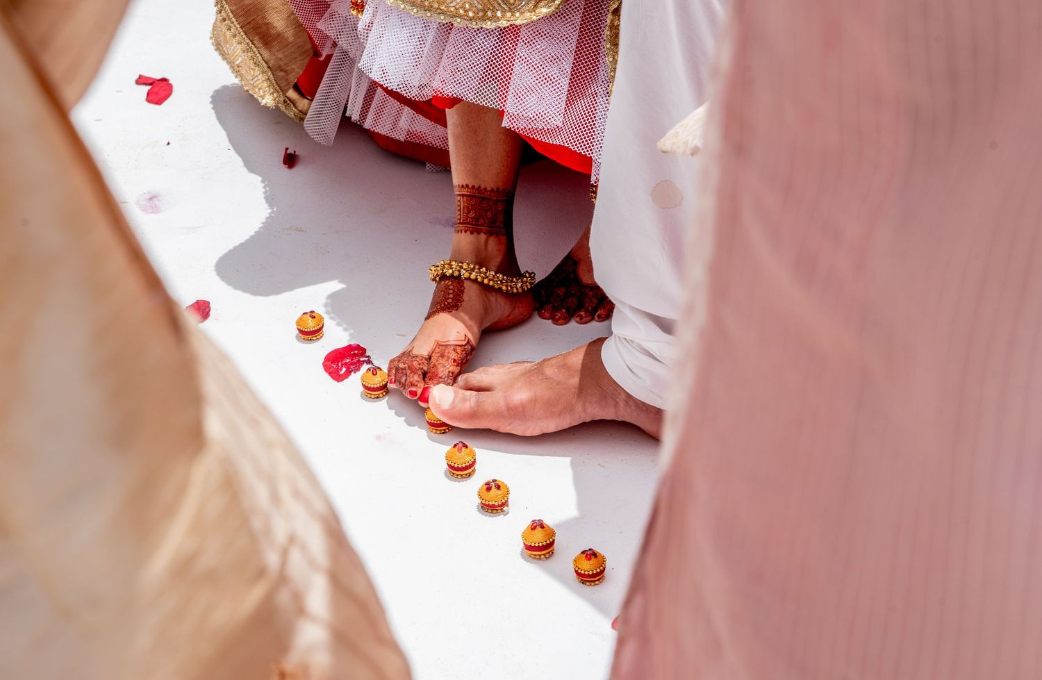 Close-up of Indian bride and groom feet during traditional Hindu wedding ceremony with mehndi and marigold flowers.