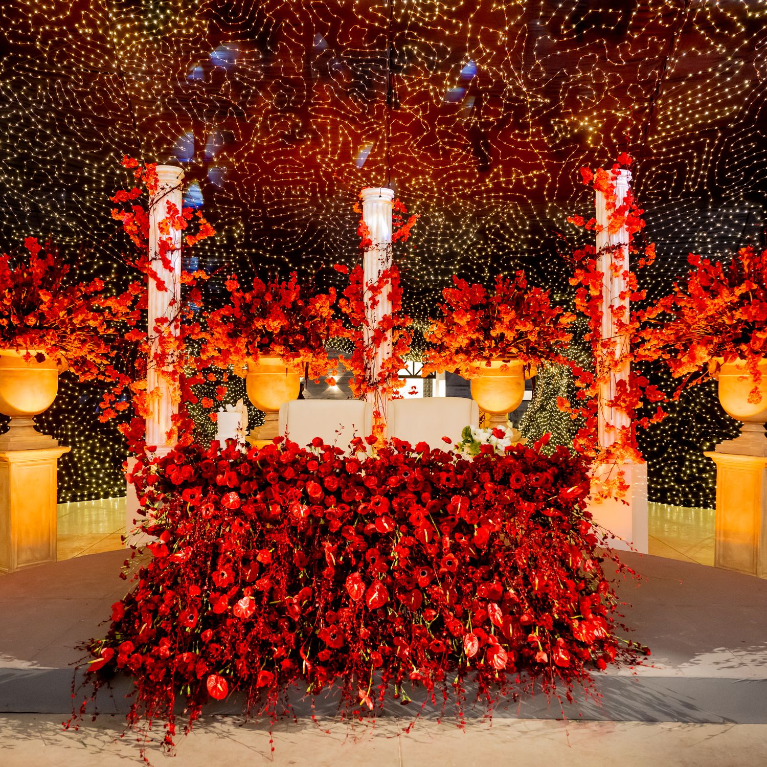 Stunning wedding reception decor featuring red floral arrangements and warm lighting.
