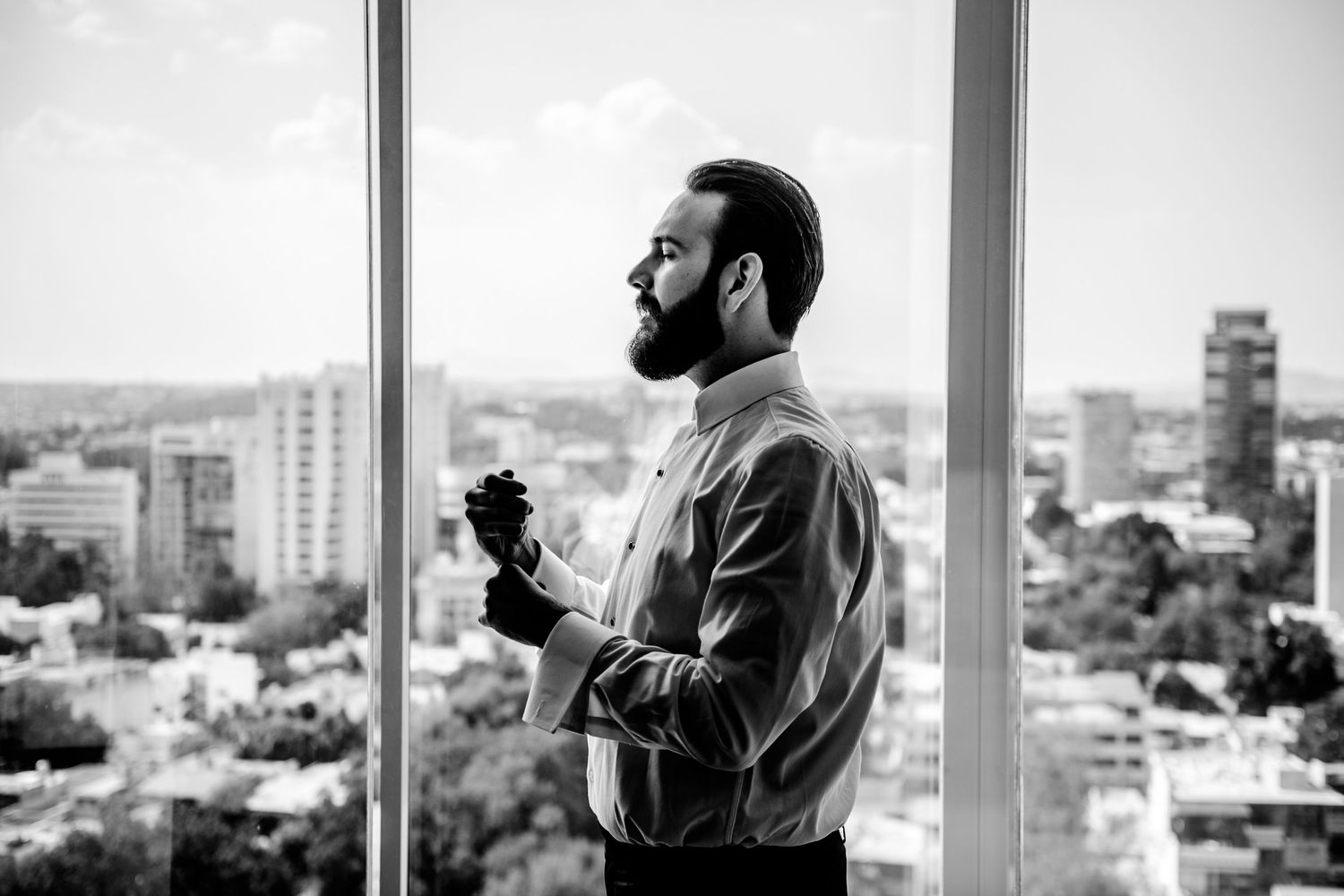 Silhouetted figure against large windows overlooking a cityscape.