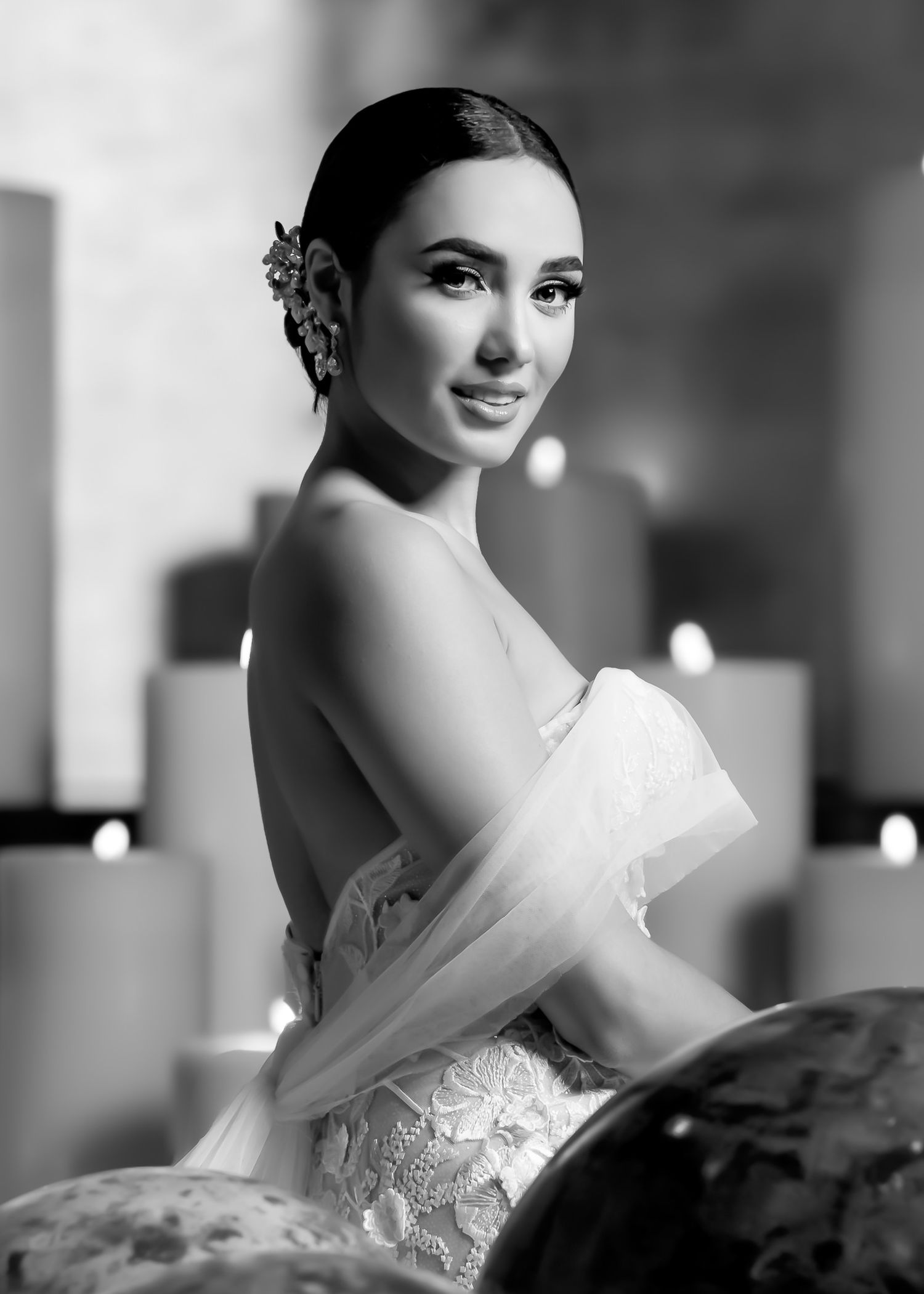 Bride in an elegant white lace wedding gown poses for artistic black and white portraits.