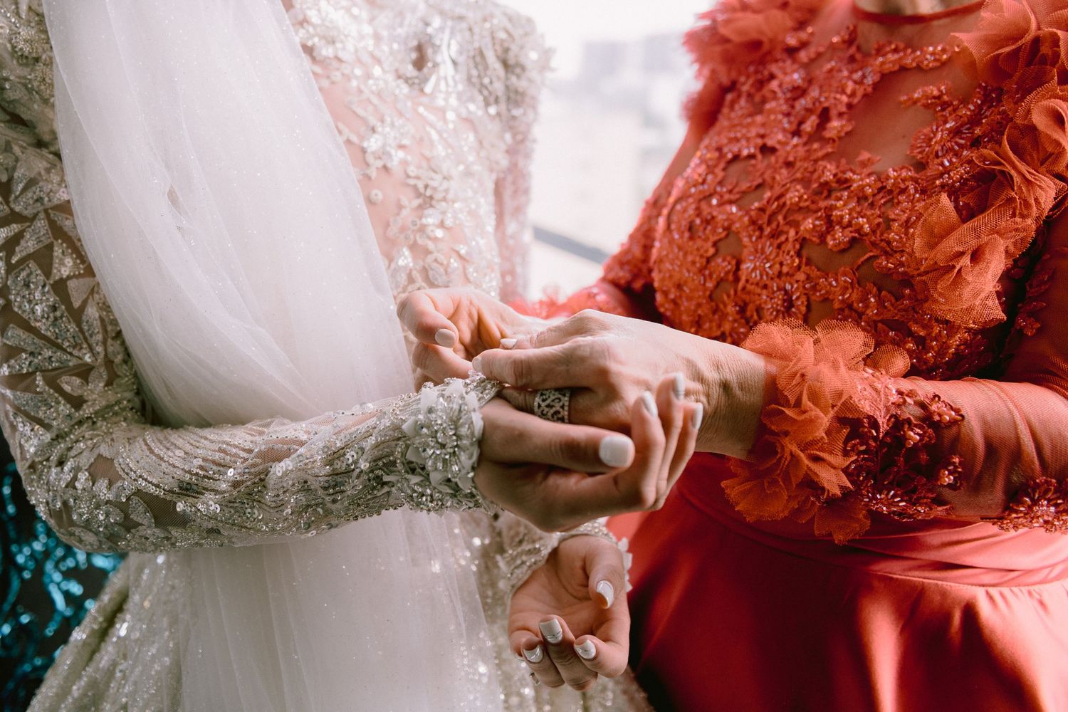 Close-up of hands exchanging rings during a wedding ceremony with ornate embroidered gowns.
