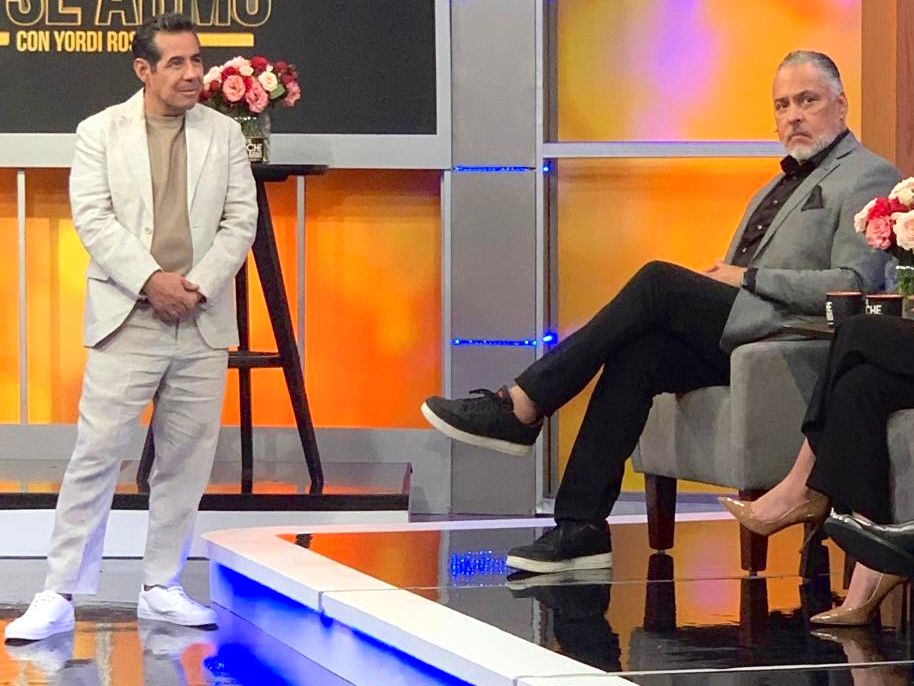 Talk show studio set featuring orange walls and contemporary seating arrangement.