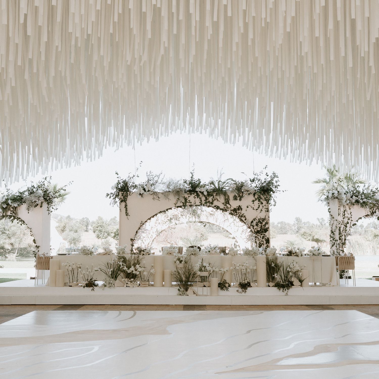 Minimalist wedding venue with white fabric ceiling drapes and delicate floral accents.