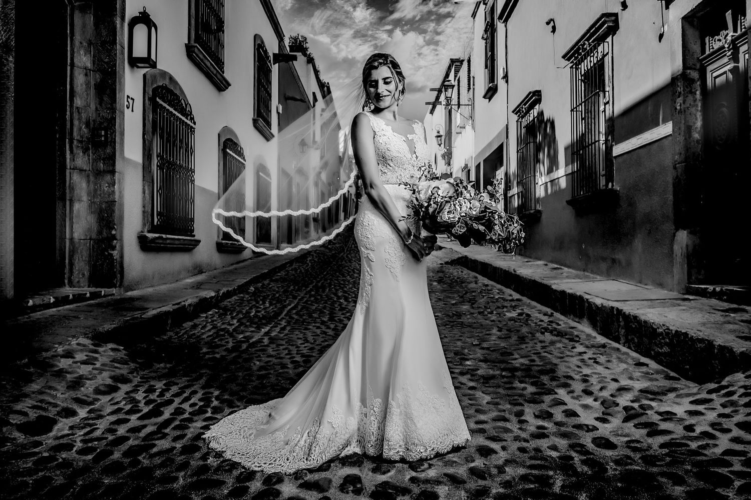 Wedding photography on cobblestone streets featuring flowing white dresses against historic architecture.