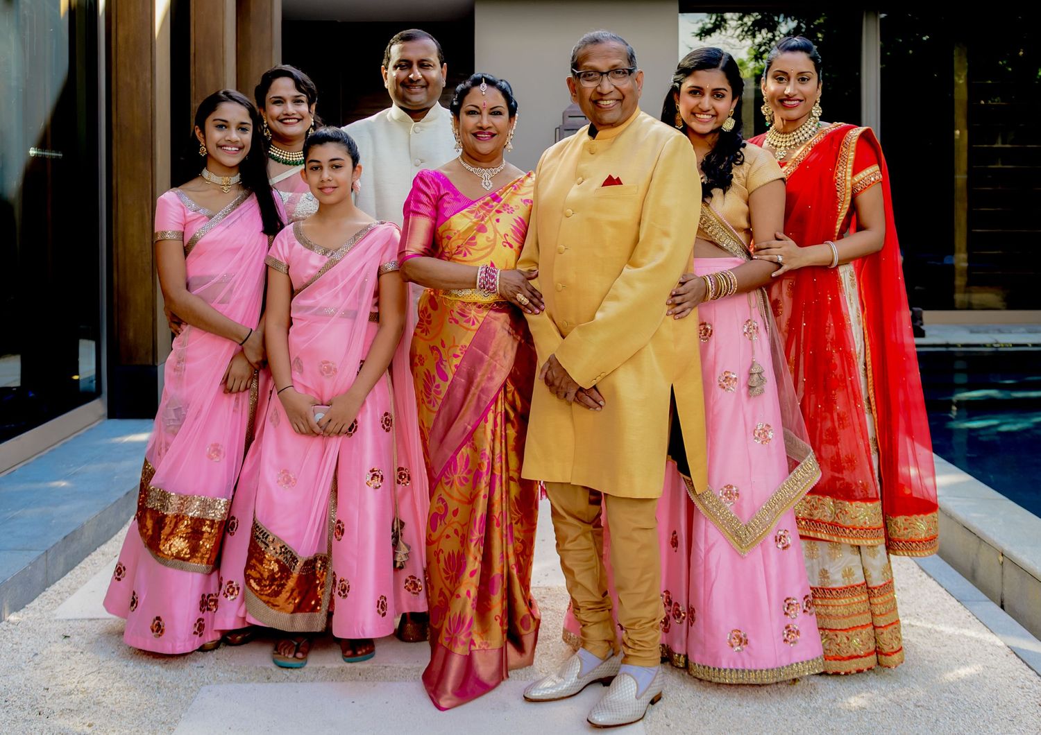 Family group photo with traditional Indian wedding attire in pink and gold.