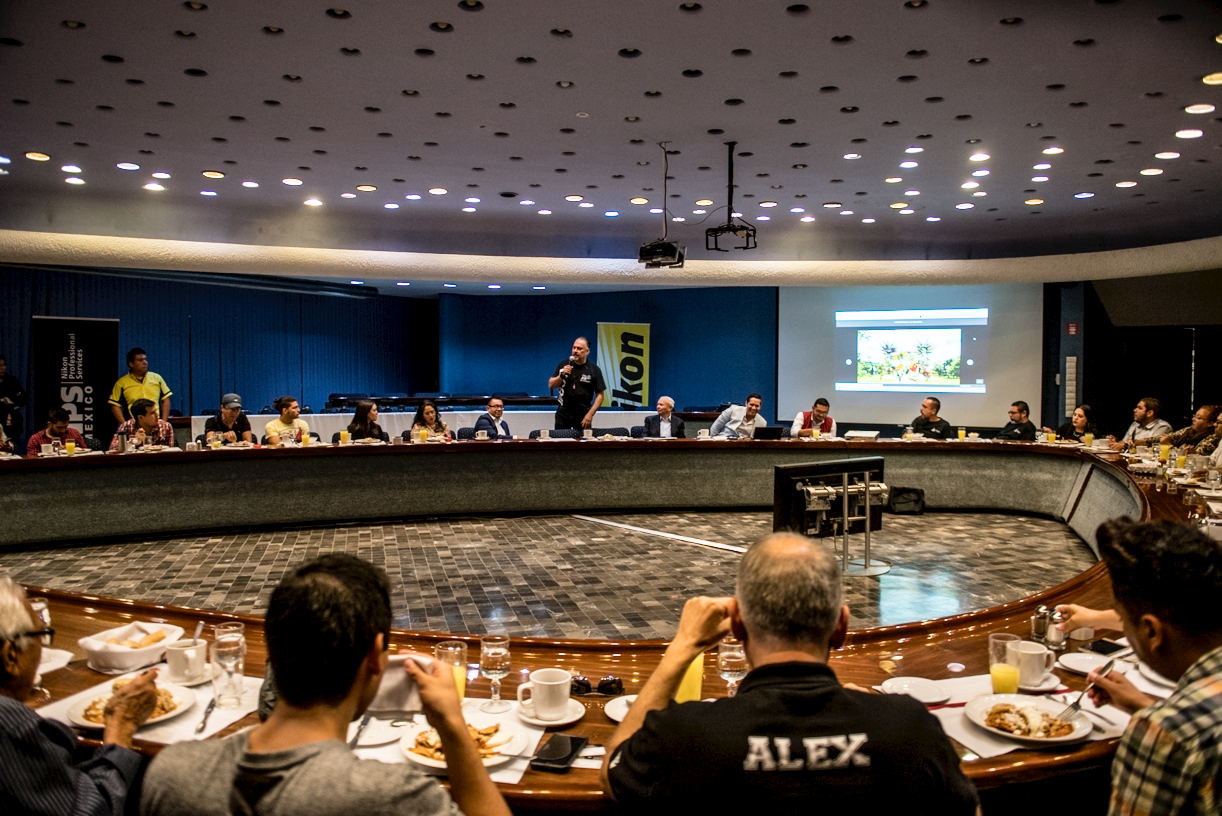 Wide angle view of a dimly lit conference room with spotlights on ceiling.