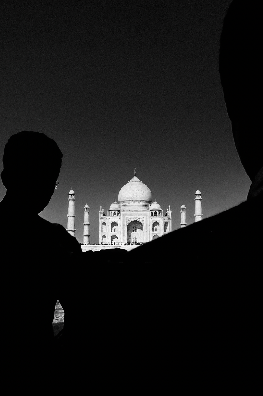 A silhouette shot of the Taj Mahal with dark figures framing the iconic monument.