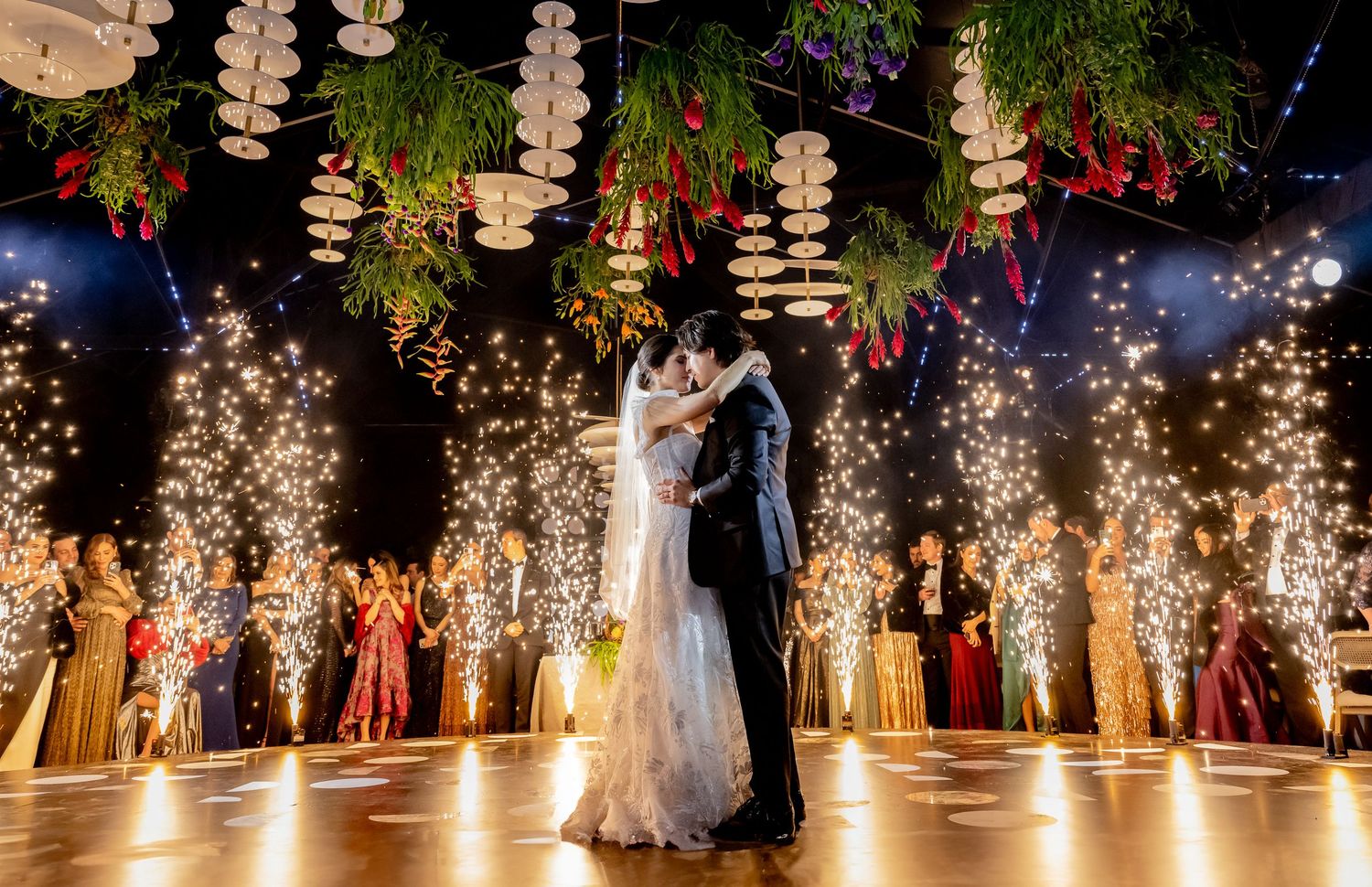 Elegant wedding reception venue decorated with hanging crystal chandeliers and warm lighting for dancing.