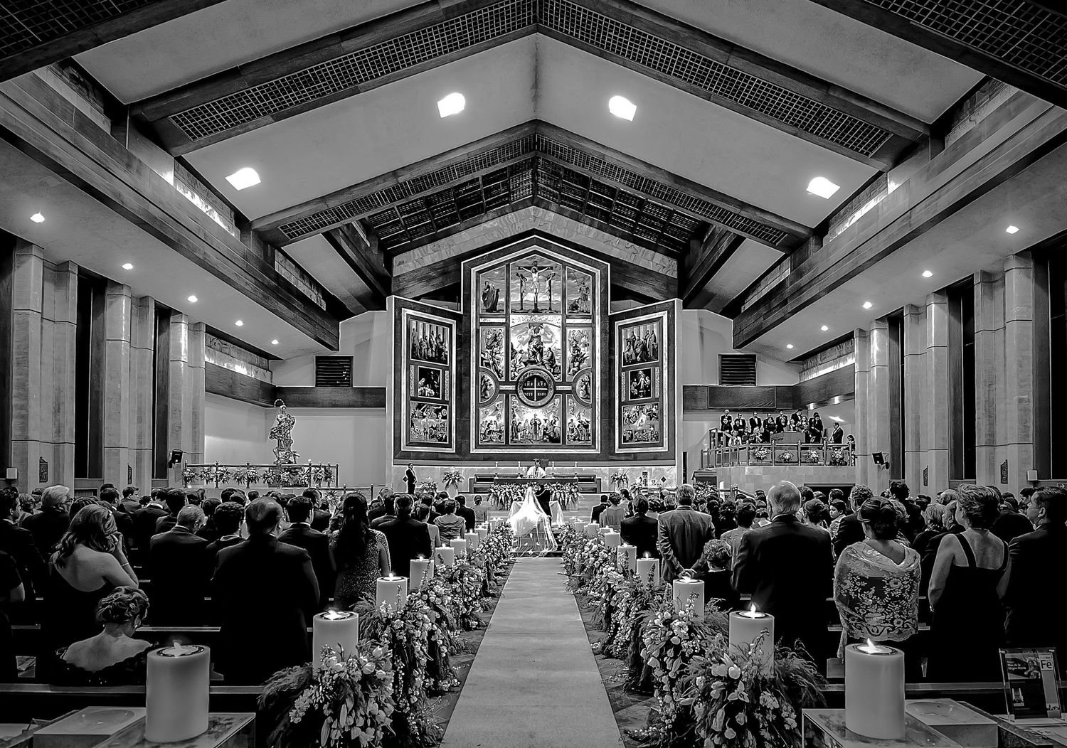 Panoramic view of church interior set up for wedding ceremony with rows of pews.