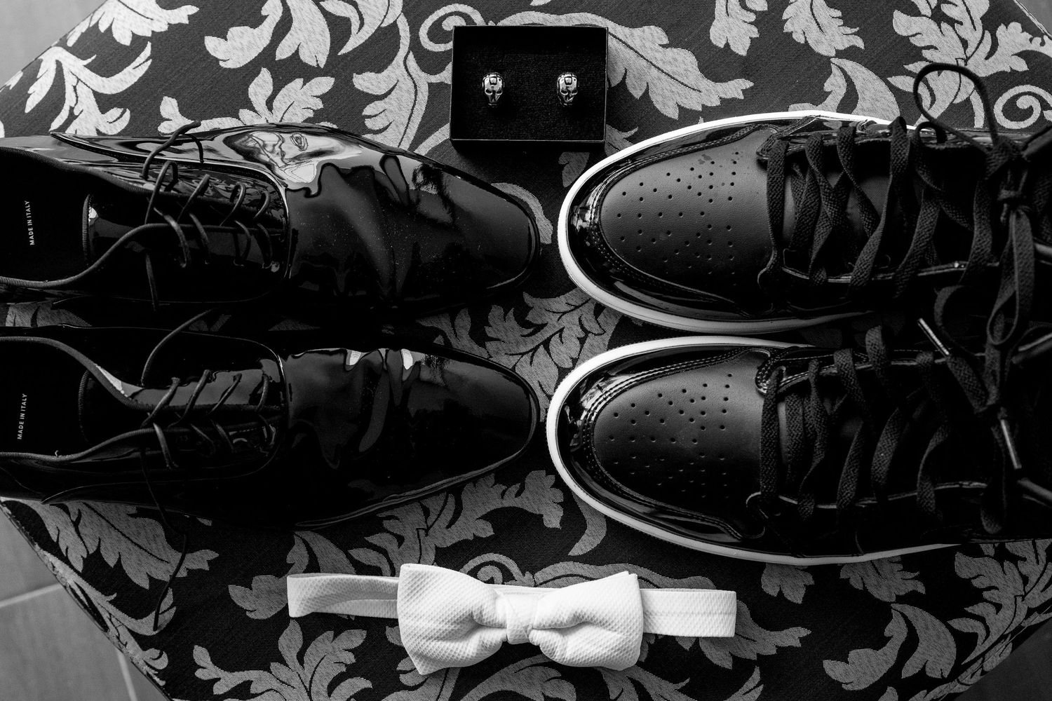 Men's formal dress shoes arranged on dark patterned fabric.